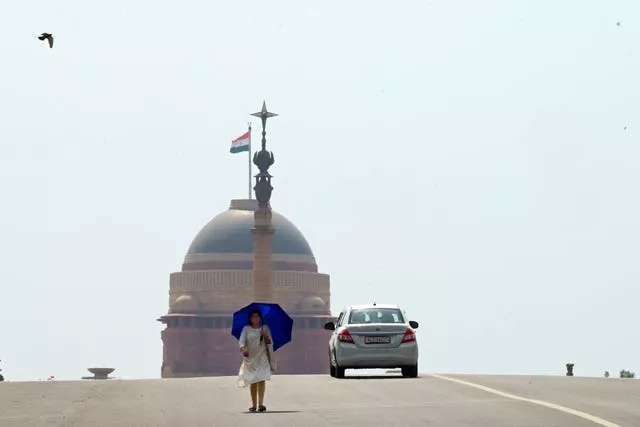 A woman walks under an umbrella as protection from severe heat in New Delhi