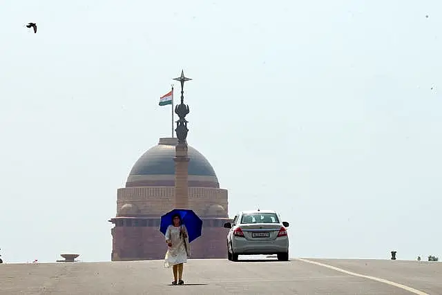 A woman walks under an umbrella as protection from severe heat in New Delhi