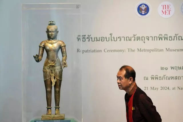 A Thai person looks at a standing Shiva sculpture from the 11th century during a repatriation ceremony at National Museum in Bangkok, Thailand