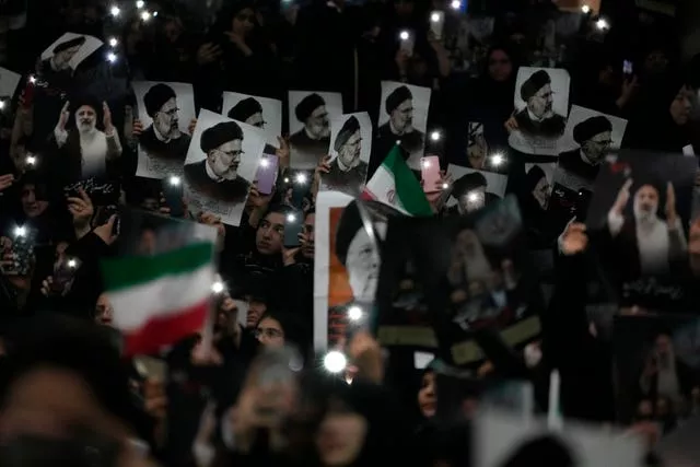 Mourners hold up a posters of the late Iranian President Ebrahim Raisi at the mam Khomeini Grand Mosque in Tehran