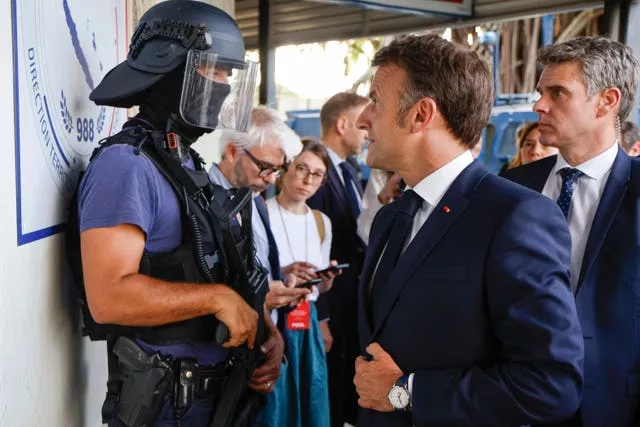 The French president speaking to a policeman at the central police station in Noumea 