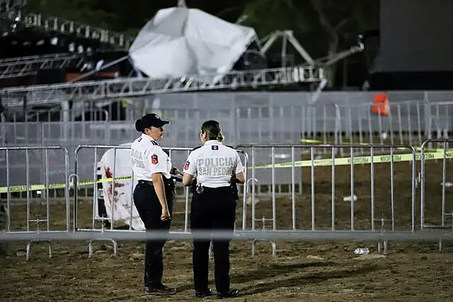 Security forces stand around the collapsed stage 