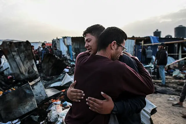 Palestinians react next to the destruction after an Israeli strike in Rafah