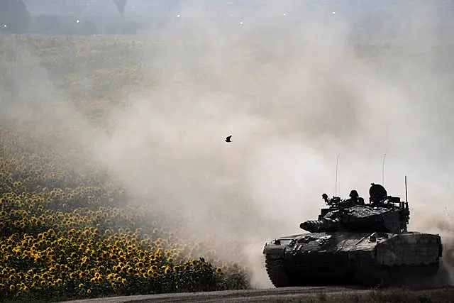 Israeli soldiers move on the top of a tank near the Israeli-Gaza border, as seen from southern Israel