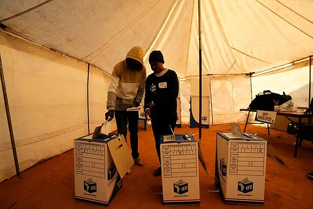 A man assisted by an electoral worker casts his ballot at a polling station in Alexandra, near Johannesburg, South Africa