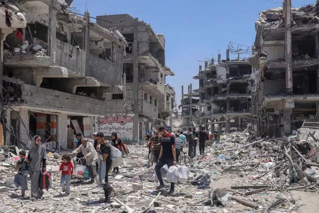 Palestinians walk through the destruction in the wake of an Israeli air and ground offensive in Jebaliya, northern Gaza Strip, in May