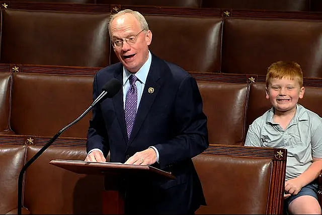 John Rose speaking on the floor of the House of Representatives as his son Guy makes a face