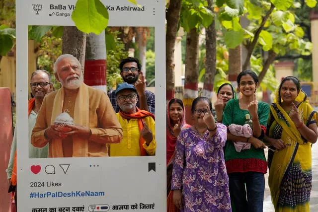 A group of voters pose for a photograph next to a cutout portrait of Indian Prime Minister Narendra Modi