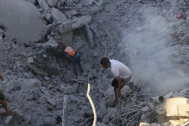 Palestinians search for bodies and survivors in the rubble of a residential building destroyed in an Israeli airstrike in Khan Younis