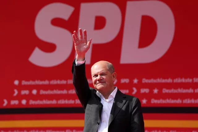Olaf Scholz stands with arm raised as he waves to supporters