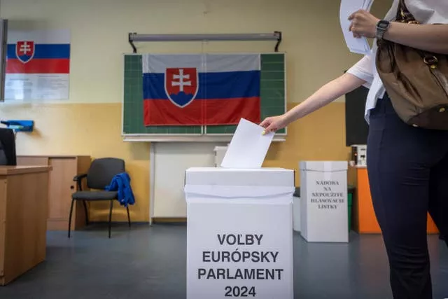 A woman slots her vote into a ballot box