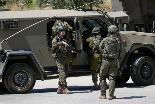 Israeli military officers gather by their vehicles in a refugee camp in the occupied West Bank