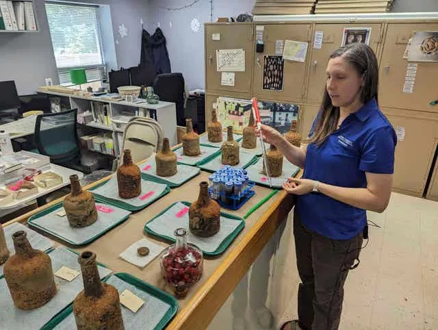 Curator Lily Carhart shows a pipette used to extract liquid from 18th-century glass bottles that contained fruit after they were unearthed from the cellar of George Washington’s residence