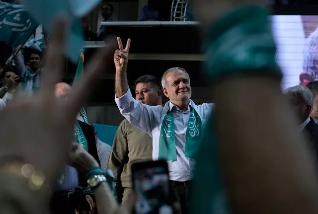 Iranian presidential candidate Masoud Pezeshkian and his supporters flash the victory sign during a campaign stop in Tehran 