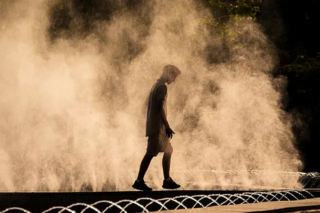 Um homem se refresca em uma fonte
