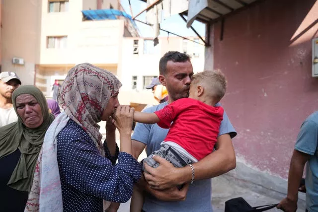 Man and woman embracing child in Gaza street