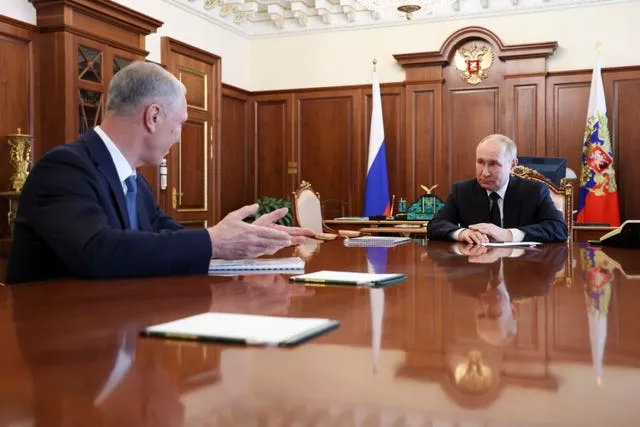 Russian President Vladimir Putin and Vladimir Saldo, Kherson governor, at wooden table in a wood-panelled room with flags behind Mr Putin