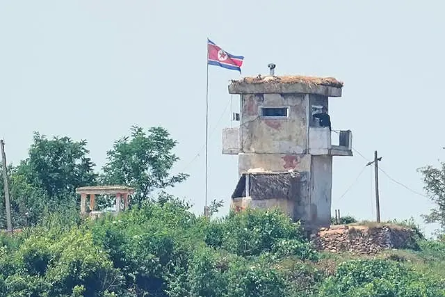 A North Korean soldier stands at the North’s military guard post as a North Korean flag flutters in the wind, seen from Paju, South Korea