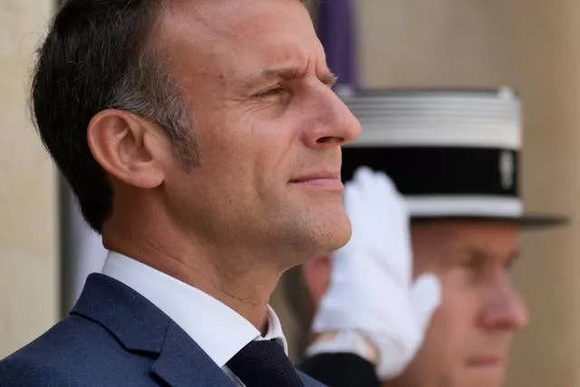 France's President Emmanuel Macron next to man in uniform saluting