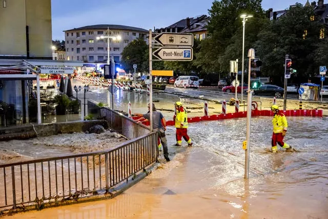 Firefighters look on as the Morges river overflows a road 