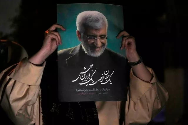 A supporter of Iranian presidential candidate Saeed Jalili holds up a poster of Jalili during his campaign stop in Tehran 