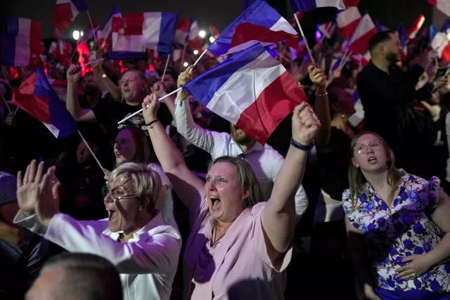 Supporters of French far right leader Marine Le Pen react after the release of projections based on the actual vote count in select constituencies 
