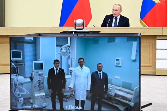 Vladimir Putin speaks to doctors, displayed on a video screen, in the Perm’s regional clinical infectious hospital during a cabinet meeting