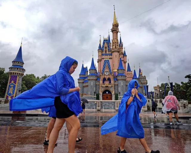 Children in blue rain jackets in front of a fairytale castle