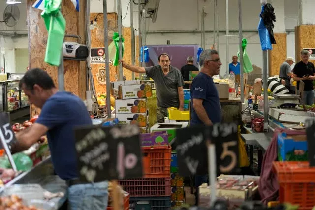 Tres hombres en un mercado de frutas y verduras.