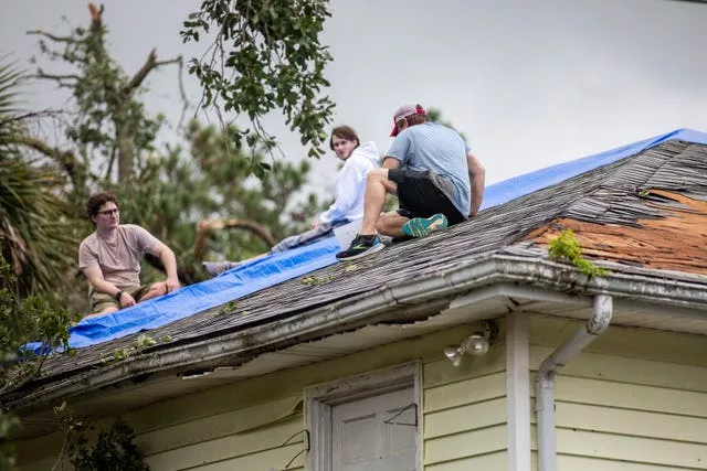 Residents repair their roof as high winds from an outer band from Tropical Storm Debby passed over the Isle of Palms in South Carolina