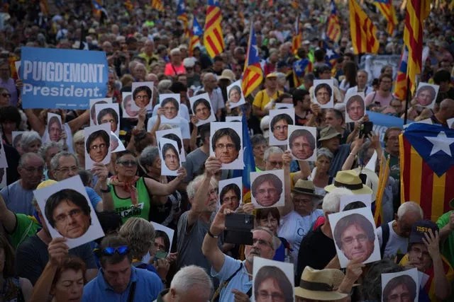 Supporters of Catalan independence leader Carles Puigdemont hold his portrait near the Catalan parliament in Barcelona on Thursday