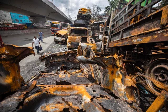 People walk past burnt vehicles beside Jatrabari Police Station