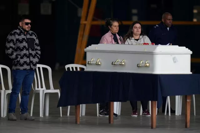 Family members of plane crash victims stand by the remains during a religious ceremony shortly before many of the victim’s remains are placed in an Air Force plane 