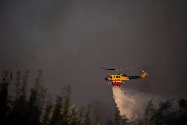 A helicopter drops water near Varnava village during a wildfire, north of Athens, Greece