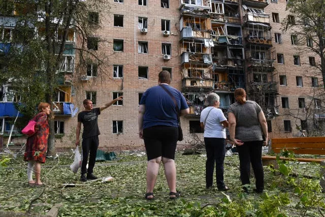 Les habitants d'un immeuble endommagé après un bombardement ukrainien se tiennent près du bâtiment à Koursk, en Russie.