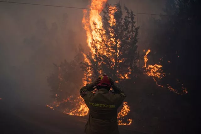 Un bombero ajusta su casco en el pueblo de Varnava durante un incendio, al norte de Atenas, Grecia