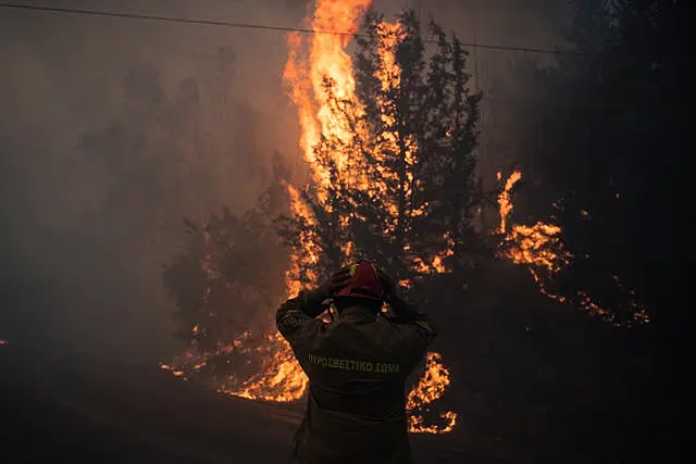 Un pompier ajuste son casque dans le village de Varnava lors d'un incendie de forêt, au nord d'Athènes, en Grèce