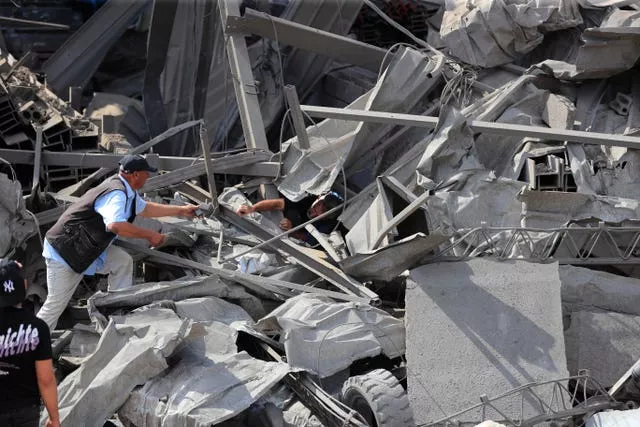 People check an industrial area destroyed by an Israeli air strike, in Wadi al-Kfour in southern Lebanon