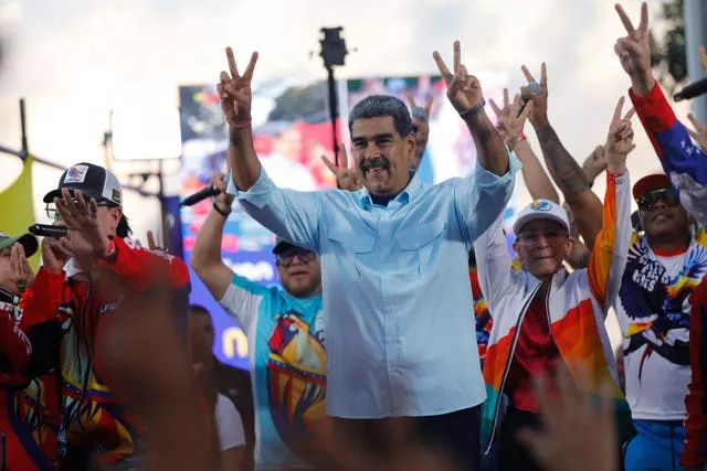 Venezuelan President Nicolas Maduro flashes victory hand signs at supporters during a pro-government rally in Caracas, Venezuela 