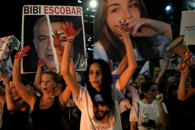 Women with fake blood on their hands, arms raised