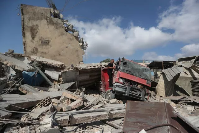 A man checks a damaged truck at an industrial area destroyed by an Israeli air strike, in Wadi al-Kfour