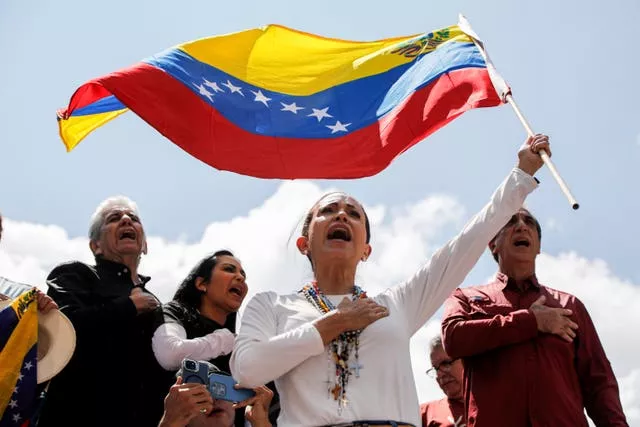 Maria Corina Machado singing while waving the Venezuelan flag