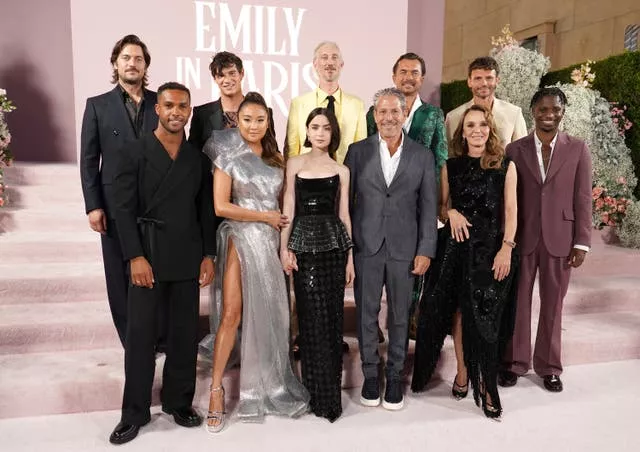 The cast of Emily in Paris smile together on lilac carpet 