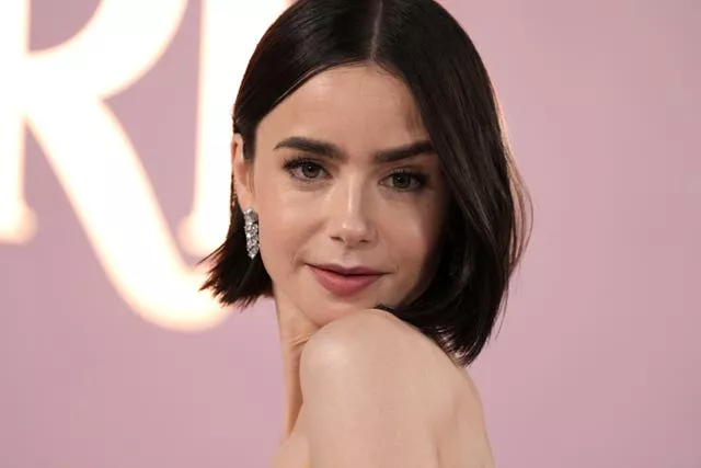 Lily Collins looks into camera with silver jewel earrings 