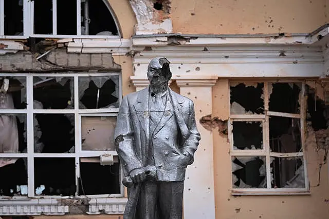 Damaged Lenin statue in front of a damaged building