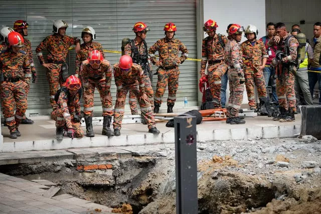 Fire and rescue officers after receiving reports that a woman had fallen into a sinkhole after a section of the pavement caved in in Kuala Lumpur, Malaysia 