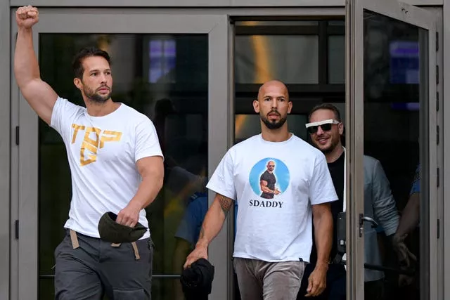 Andrew Tate, centre, and his brother Tristan, left, exit the Bucharest Tribunal after being placed under house arrest, in Bucharest, Romania