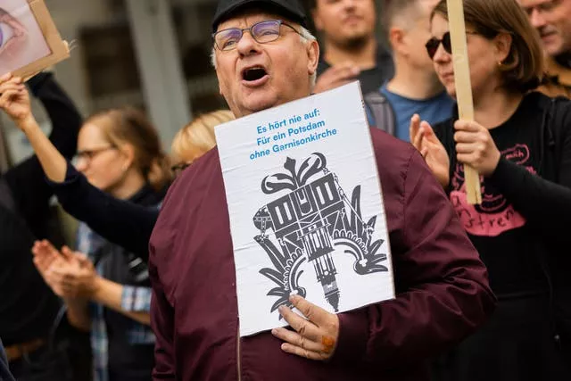 A participant in a protest organised by the Citizens’ Initiative for a Potsdam without a Garrison Church holds a sign at the opening of the church’s tower in Potsdam 