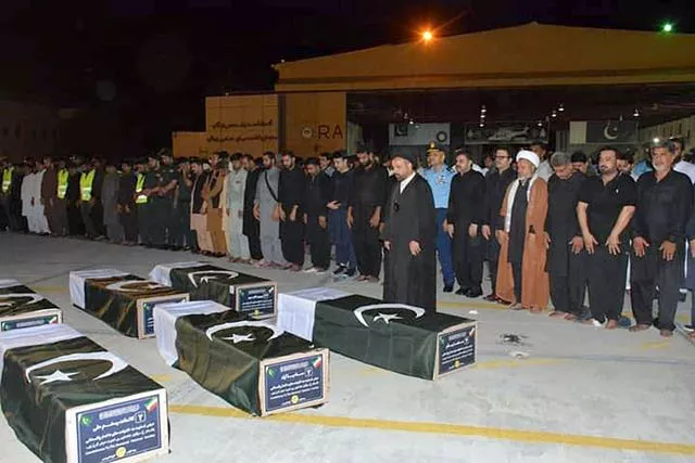 A group of men stand by six coffins