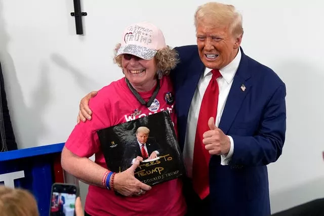 Donald Trump, right, poses with a supporter during a stop at a campaign office